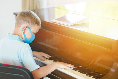 Rear view of boy playing piano