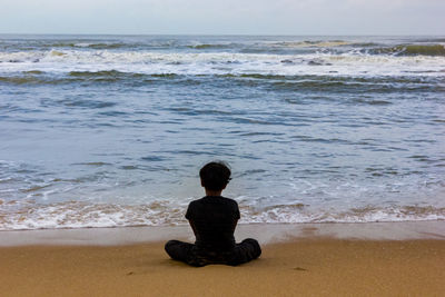 Rear view of man sitting on beach