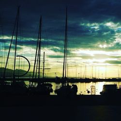 Silhouette of boats moored at harbor during sunset