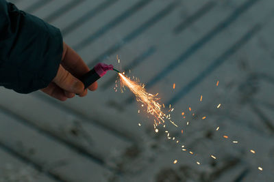 Cropped hand of young man holding sparkler