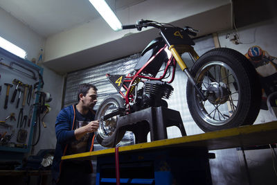 Low angle view of engineer repairing motorcycle at garage