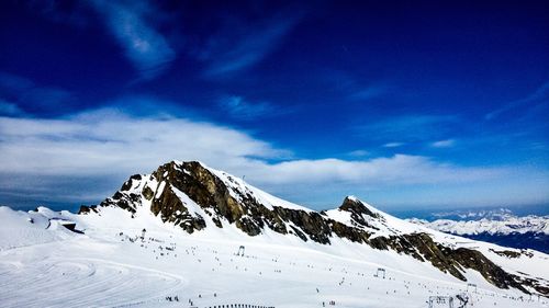 Scenic view of snowcapped mountains against blue sky