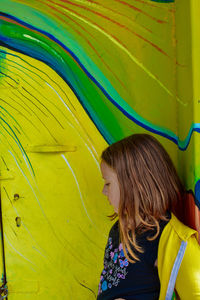 Girl standing against painting on wall