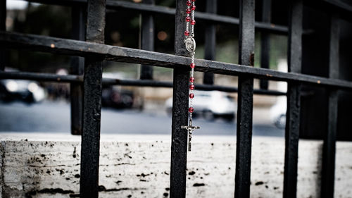 Close-up of crucifix necklace hanging on fence