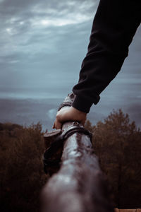 Low section of person on rock by sea against sky