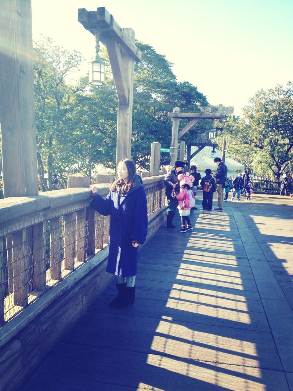 lifestyles, leisure activity, full length, tree, person, men, casual clothing, walking, togetherness, rear view, built structure, sunlight, park - man made space, railing, sky, day, large group of people, architecture