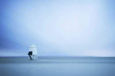 Lighthouse by sea against sky