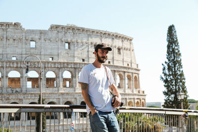 Young man standing against railing in city