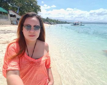 Portrait of smiling young woman in sunglasses at beach