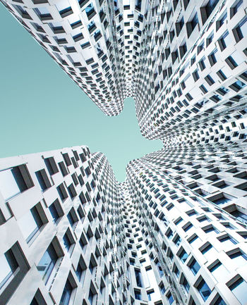 DIRECTLY BELOW VIEW OF MODERN BUILDINGS AGAINST BLUE SKY