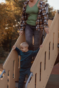 Little boy with down syndrome going down the stairs on the playgroundk with his mother