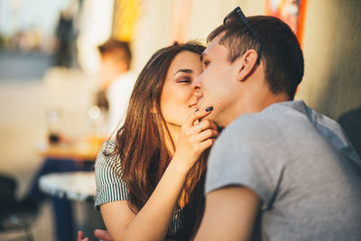 Young couple kissing while sitting at sidewalk cafe