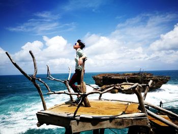 Woman standing on pier over sea against sky