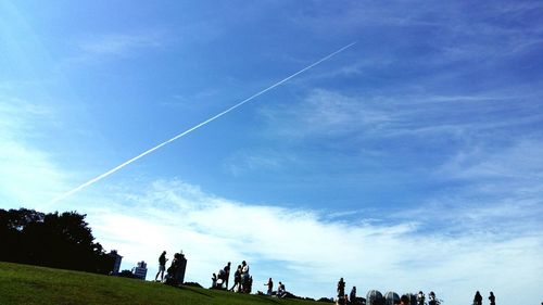 Low angle view of people against blue sky