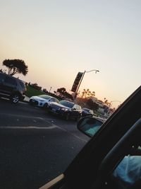 Vehicles on road against clear sky during sunset