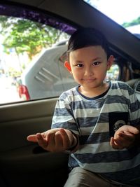 Portrait of boy gesturing while sitting in car