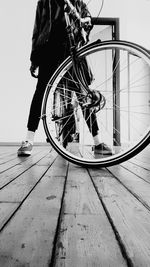 Low section of man sitting on bicycle against sky