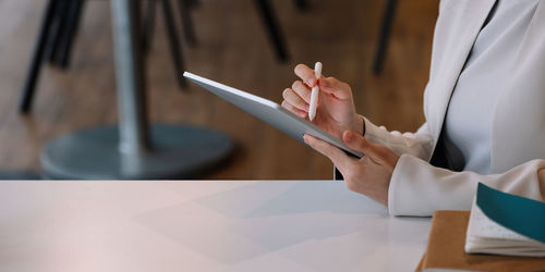 Midsection of woman using smart phone on table