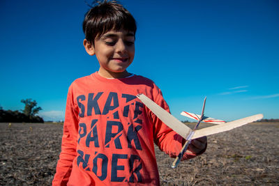 Boy holding airplane against sky