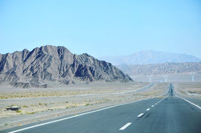 Road by mountains against clear sky