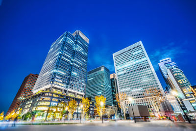 Low angle view of illuminated buildings against clear blue sky