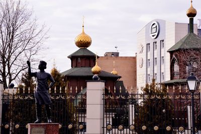 Statue of buildings in city against sky