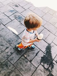 High angle view of boy sitting on footpath