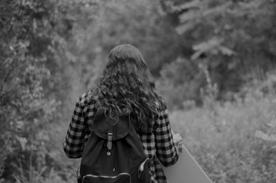 Rear view of woman standing against trees