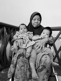 Portrait of grandmother with grandchildren sitting on balcony