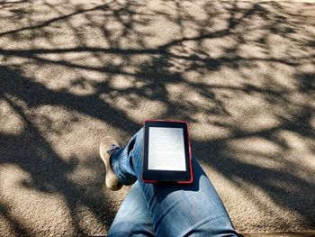 Low section of woman with digital tablet on road