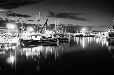 Boats moored in illuminated harbor at night