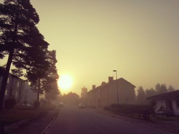 Cars on road against clear sky during sunset