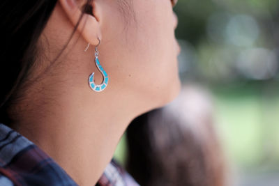 Cropped image of woman wearing blue earing