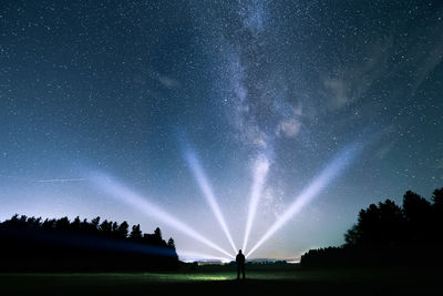 Silhouette trees on field against sky at night