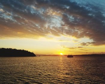 Scenic view of sea against dramatic sky during sunset