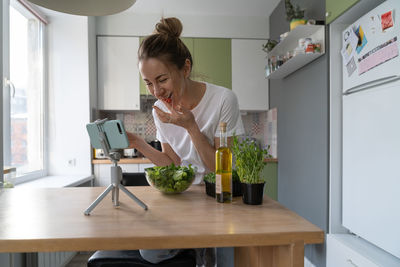 Smiling woman vlogging at kitchen