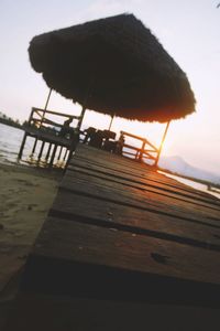 Close-up of bird on pier against sky at sunset