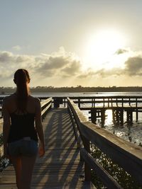 Rear view of woman standing on pier against sky