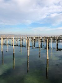 Wooden poles in water against sky