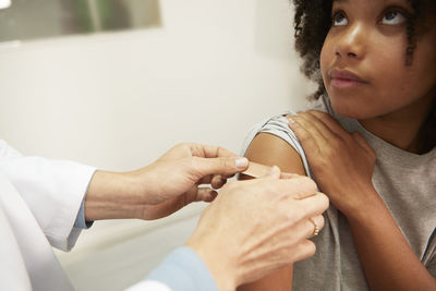 Doctor applying adhesive bandage on patient's arm in medical room