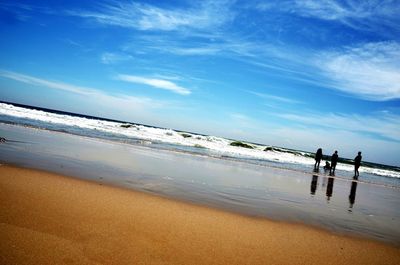 People standing on beach against sky