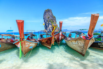 Fishing boat moored on beach against blue sky