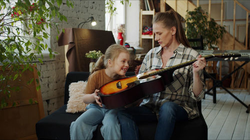 Mother teaching guitar to daughter