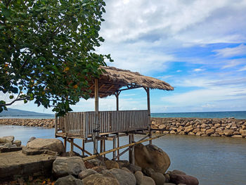 Gazebo on rocks by sea against sky