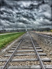 Surface level of railway tracks against cloudy sky