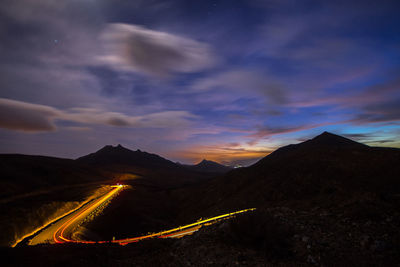 Aerial view of illuminated mountains against sky at sunset