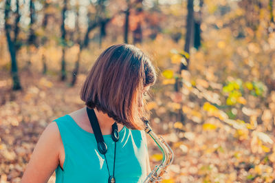 Midsection of woman with autumn leaves in forest