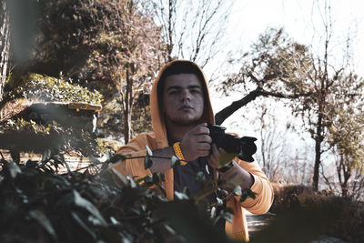 Portrait of young man holding plants in forest