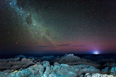 Scenic view of rocky shore against sky with star field at night