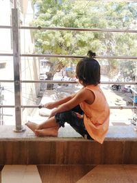Rear view of woman sitting on glass window